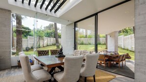A modern dining area with a glass table and chairs, a view of the backyard, and a large window. - Casa María (Valle de Bravo)