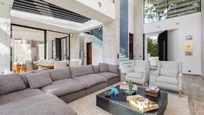 A modern living room with a large sectional sofa, a coffee table, and a staircase leading to an upper level. - Casa María (Valle de Bravo)