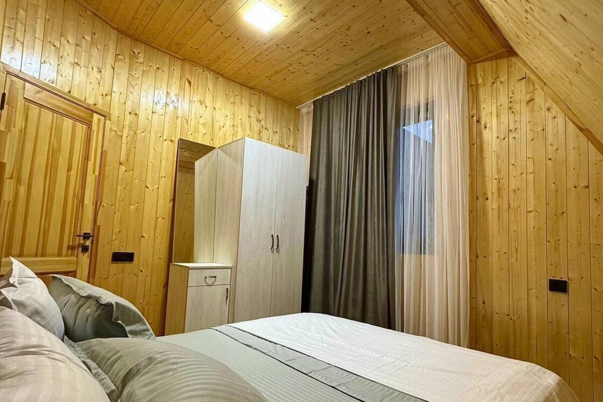 Una stanza con rivestimenti in legno, un letto, un armadio e una finestra con tende.