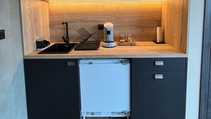 Een kleine keuken met een magnetron, koffiezetapparaat en vaatwasser.