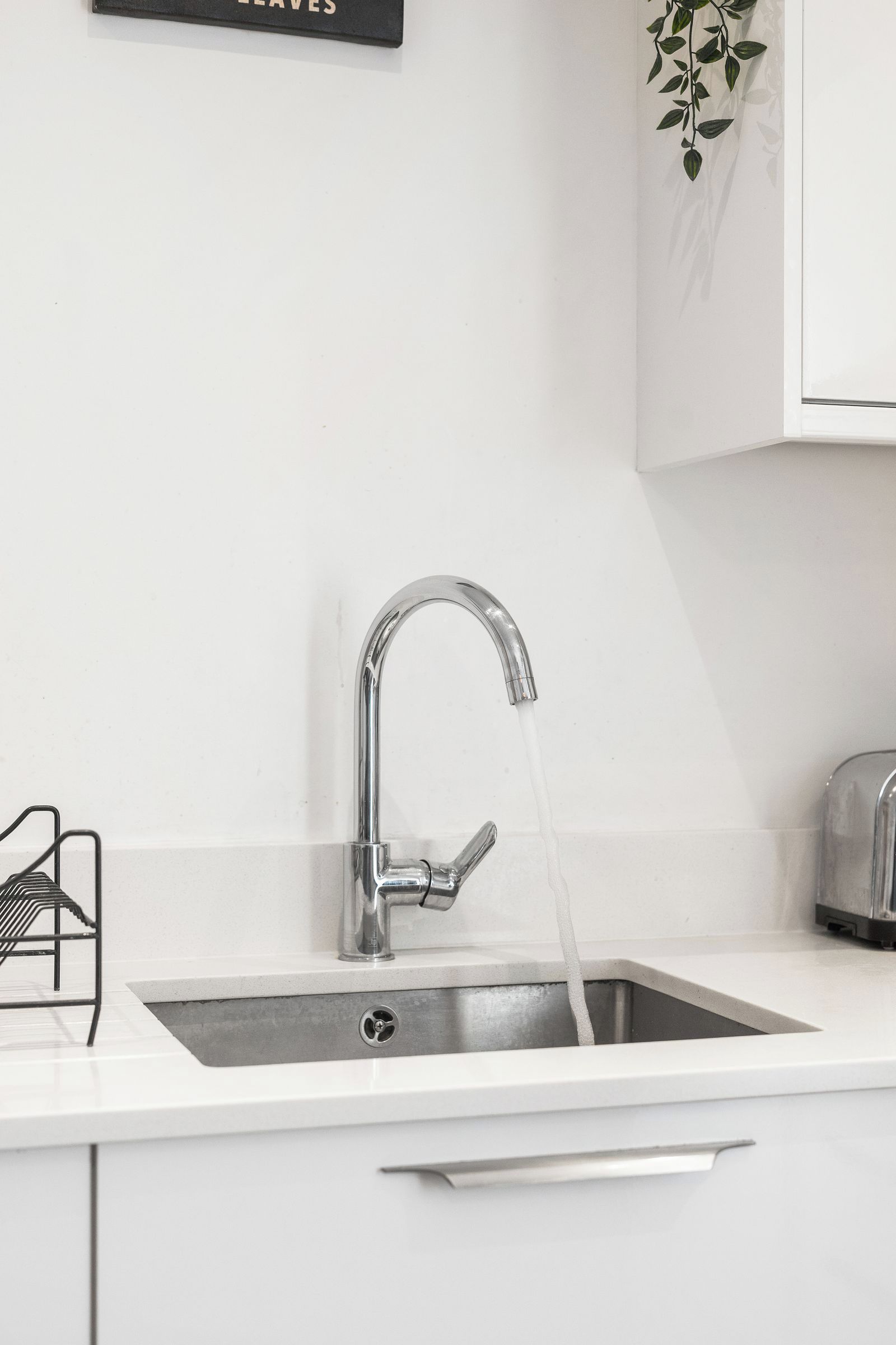 A modern kitchen with a stainless steel sink, a faucet, and a toaster.
