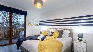 Ett sovrum med en säng, sängbord, ett fönster med utsikt och en randig väggdesign.