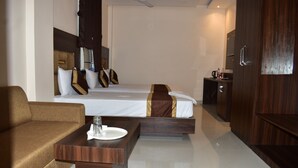 A modern hotel room with a bed, a sofa, a small table with a glass, and a wardrobe. - HOTEL KUSUM PALACE (Gaya)