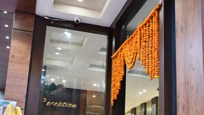 A reception area with a glass door, a reception desk, and a chair. - HOTEL KUSUM PALACE (Gaya)