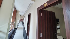 A hotel corridor with a wooden door labeled "101" and a metal railing. - HOTEL KUSUM PALACE (Gaya)