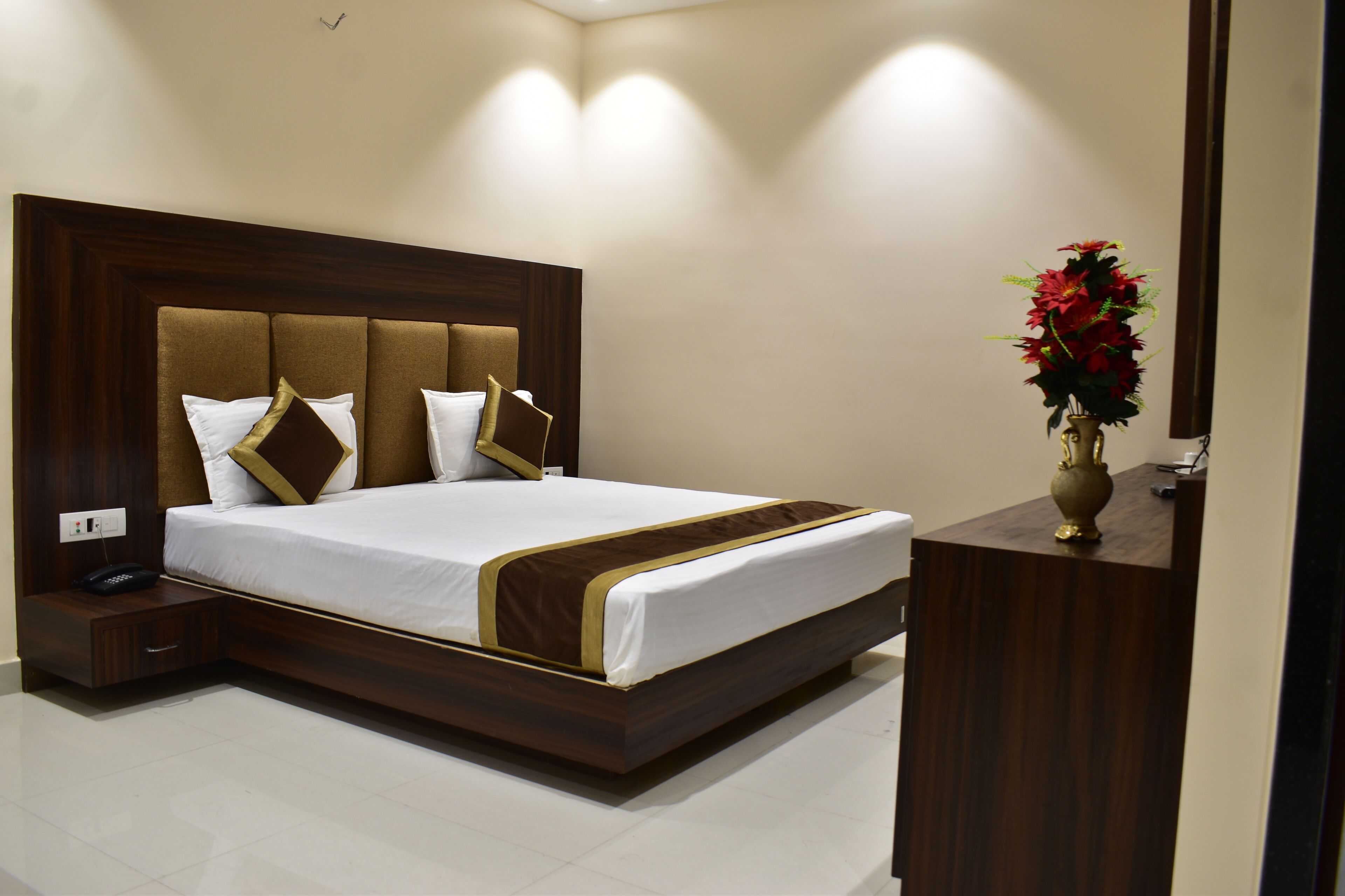 Habitación de hotel moderna con una cama grande, cabecero de madera y una mesita de noche con teléfono.