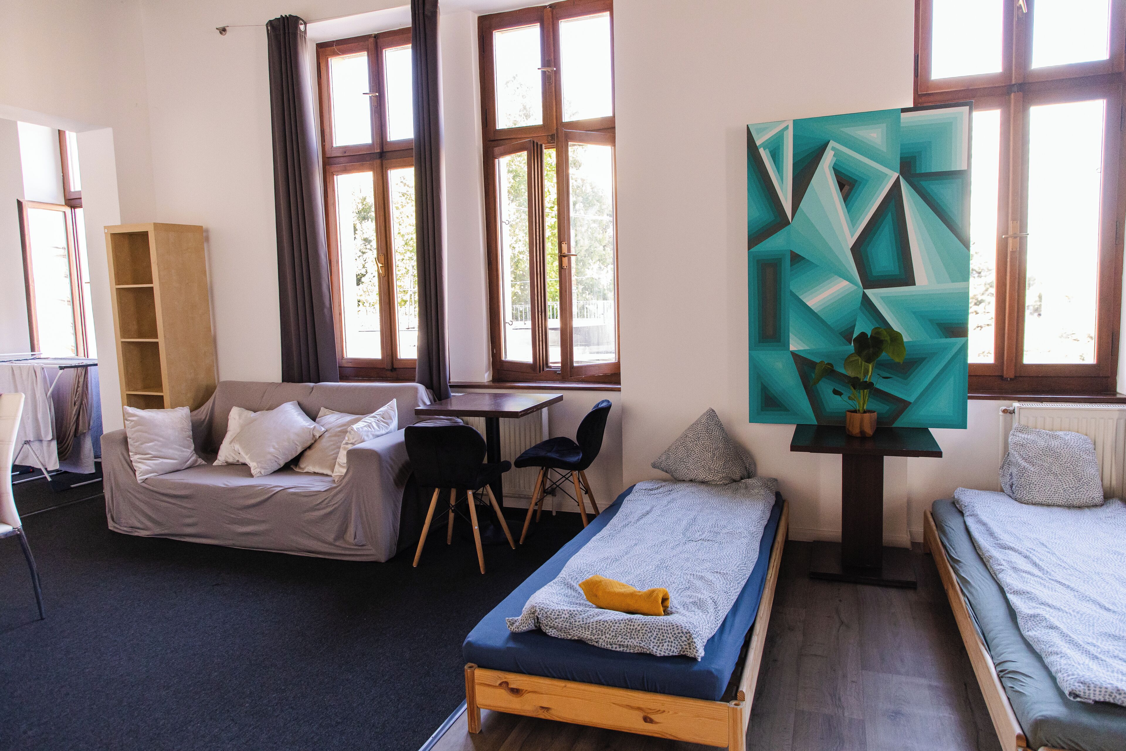 A modern room with a bed, a sofa, a desk, and a large window.