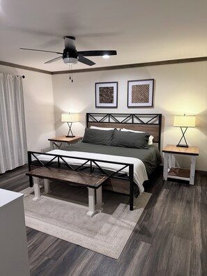 Een slaapkamer met een bed, nachtkastjes, een plafondventilator en een bank.