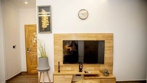 Una sala moderna con un mueble de madera para entretenimiento, un televisor de pantalla plana, una planta en maceta y una mesa de centro redonda de madera.