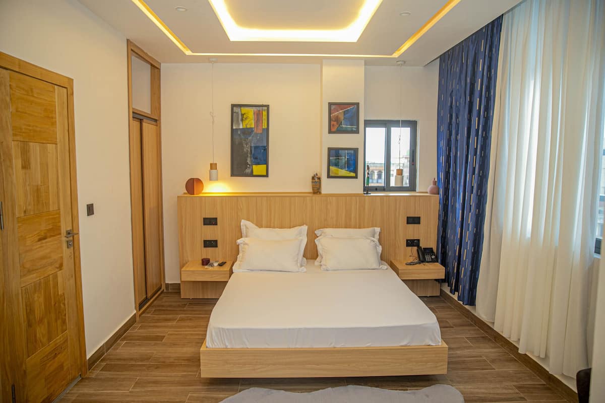 Una camera da letto moderna con un letto grande, una testiera in legno, comodini e opere d'arte alle pareti.