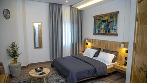 Un dormitorio moderno con una cama grande, mesitas de noche, un espejo y un cuadro en la pared.