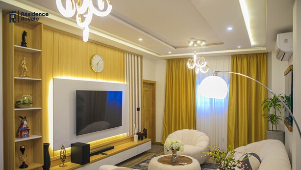 Una sala de estar moderna con un televisor de pantalla plana, asientos cómodos y elementos decorativos.