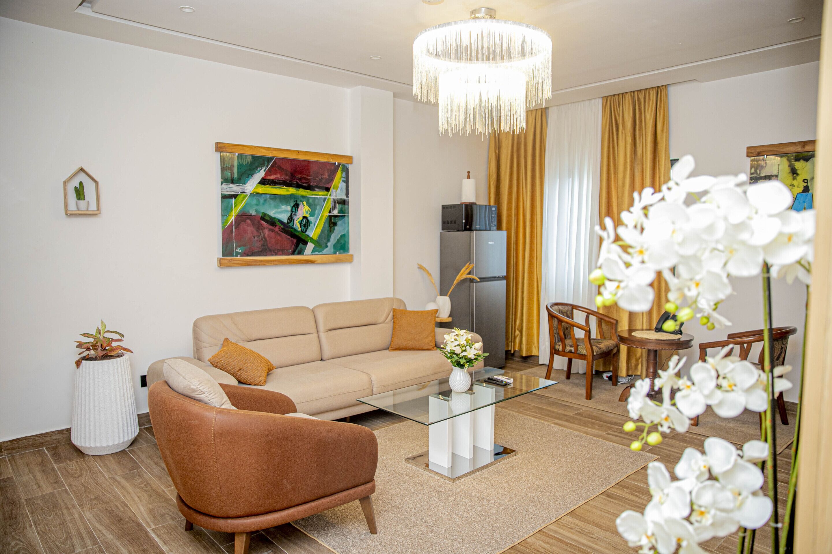Una sala de estar moderna con un sofá, un sillón, una mesa de centro de vidrio y una araña.