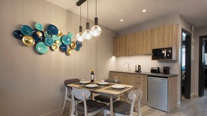 Une cuisine moderne avec un coin repas, comprenant un meuble en bois, un four à micro-ondes encastré et un luminaire fixé au mur.