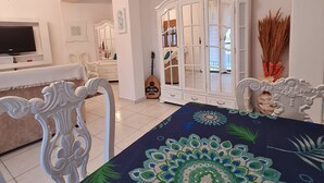 A spacious living room with a large TV, white furniture, and a decorative cabinet.