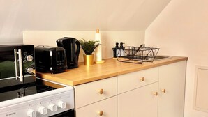 A kitchen with a white stove, black coffee maker, and a black kettle on the countertop.