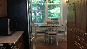 A kitchen with a refrigerator, stove, and dining table with chairs.