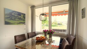 A dining area with a glass-top table, brown leather chairs, a fruit bowl, and a hanging light fixture. - Your perfect getaway for a relaxing vacation, including Unlimited Mountain Rail Pass (Oberstdorf)