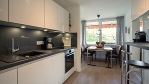 A modern kitchen with a built-in oven, a sink, and a dining area with a table and chairs. - Your perfect getaway for a relaxing vacation, including Unlimited Mountain Rail Pass (Oberstdorf)