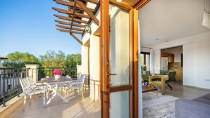 A modern apartment with a balcony, a dining area, and a living room. - Bright Apartment With Shared Pool in Aphrodite Hills (Kouklia)