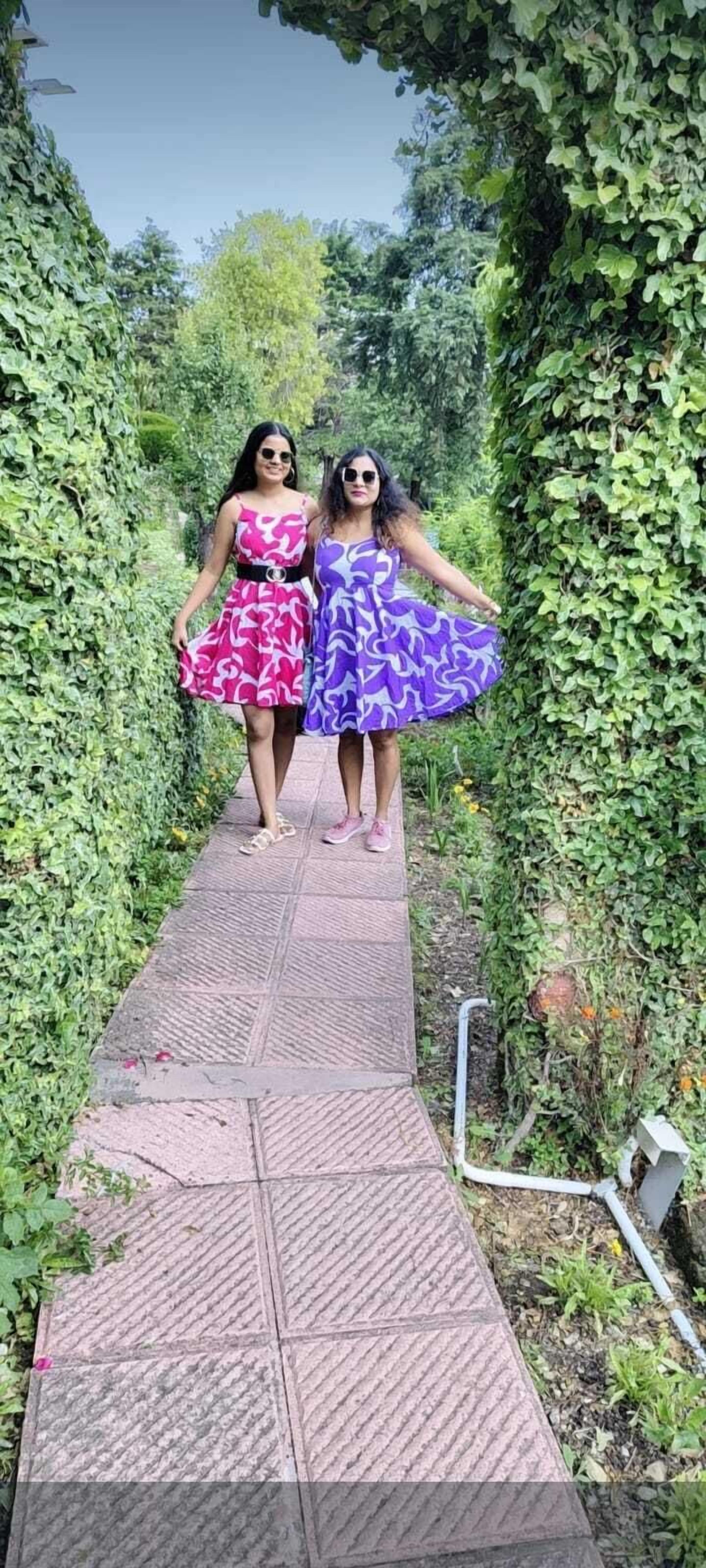 Two women walking on a paved path surrounded by greenery.