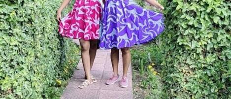 Two women walking on a paved path surrounded by greenery.
