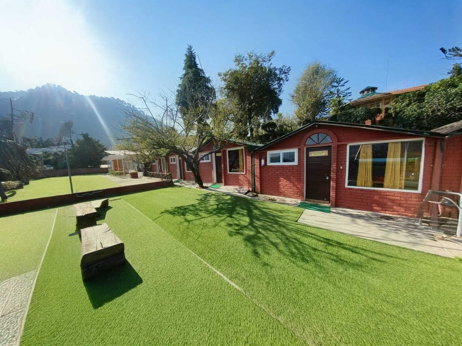 A red brick building with a green lawn, a bench, and a small tree.