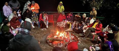 Un grupo de personas reunidas alrededor de una fogata en un entorno exterior de noche.