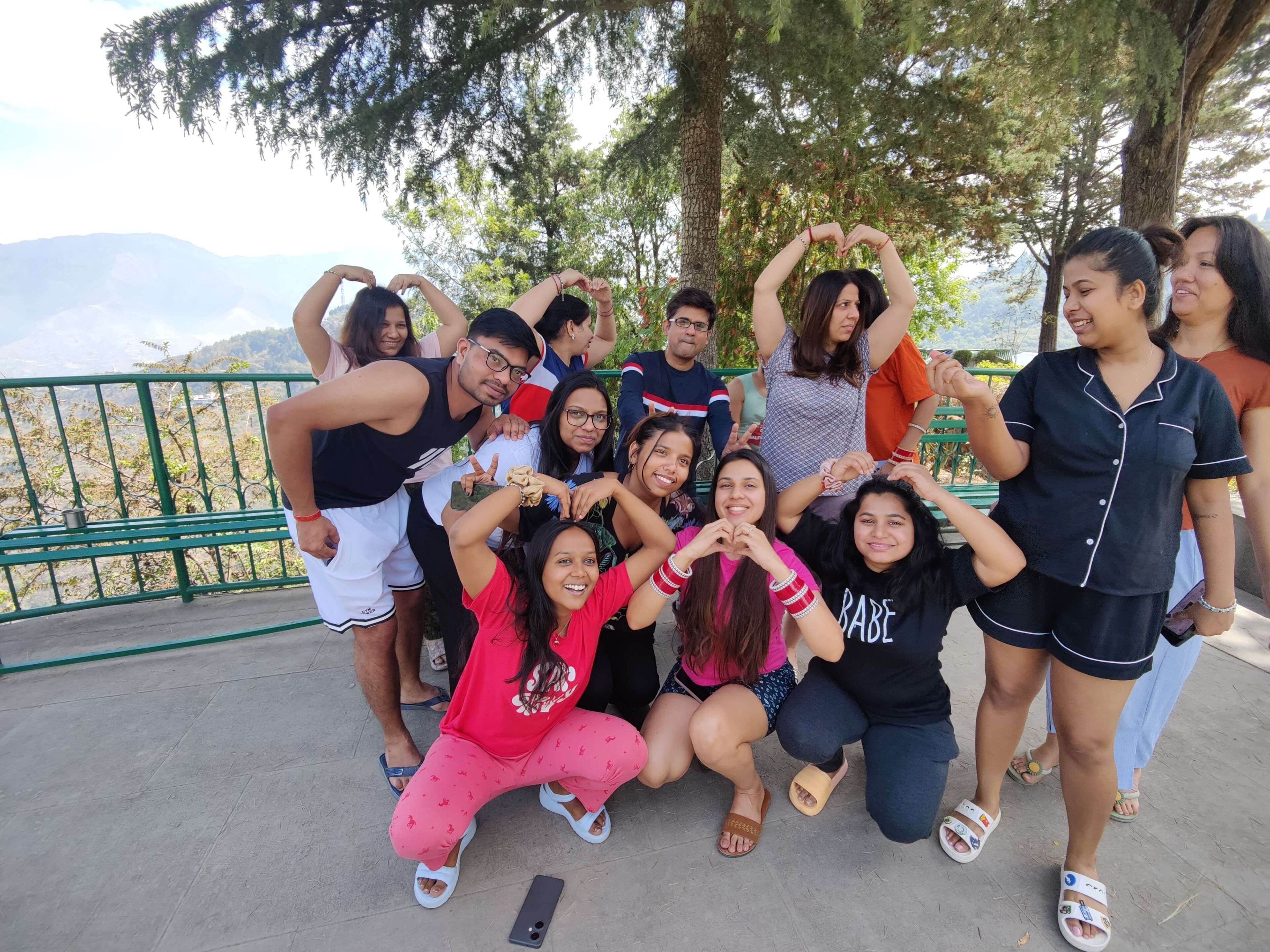 A group of people posing outdoors with a railing and trees in the background.
