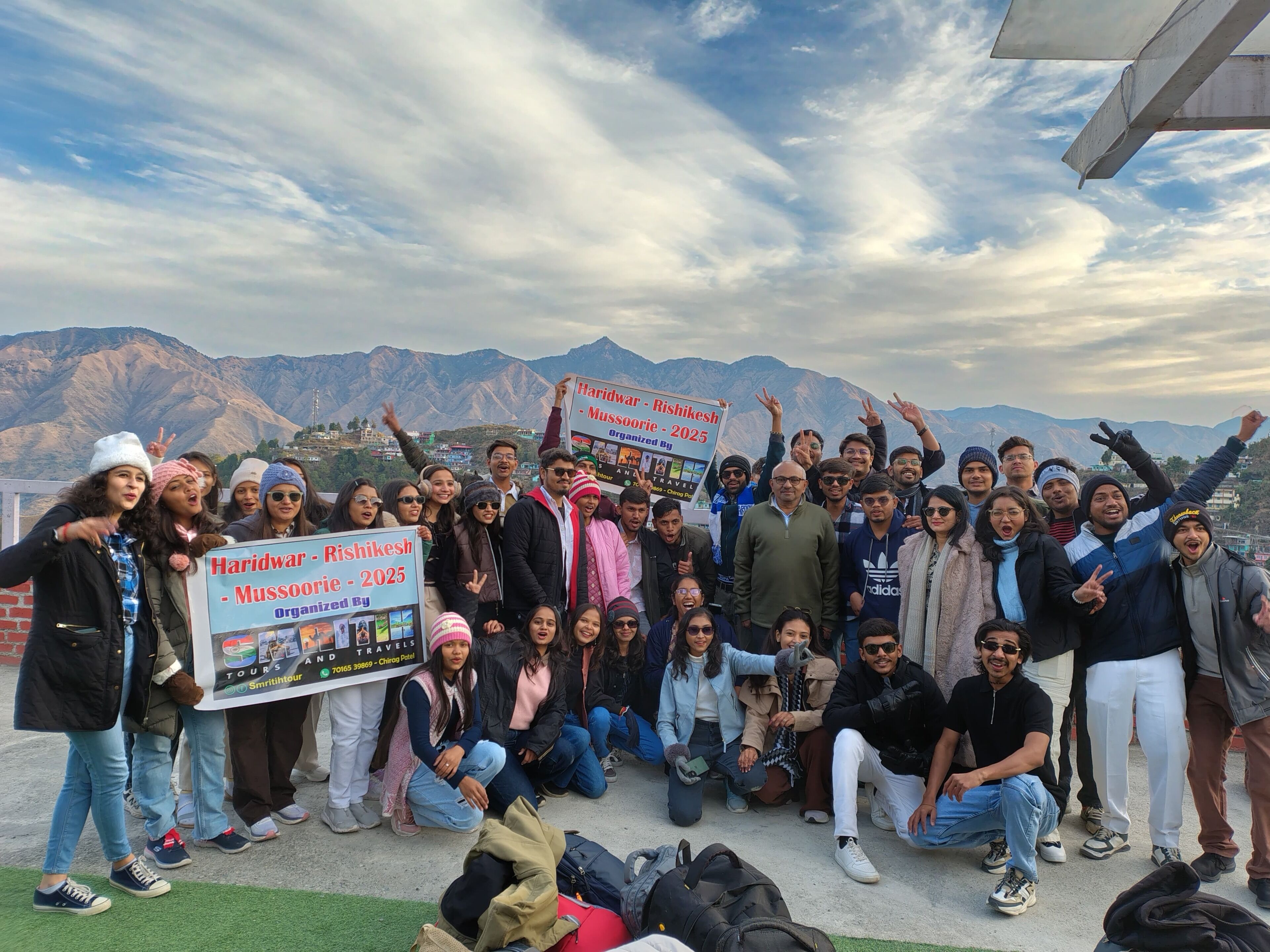 A group of people posing with a signboard in a mountainous area.