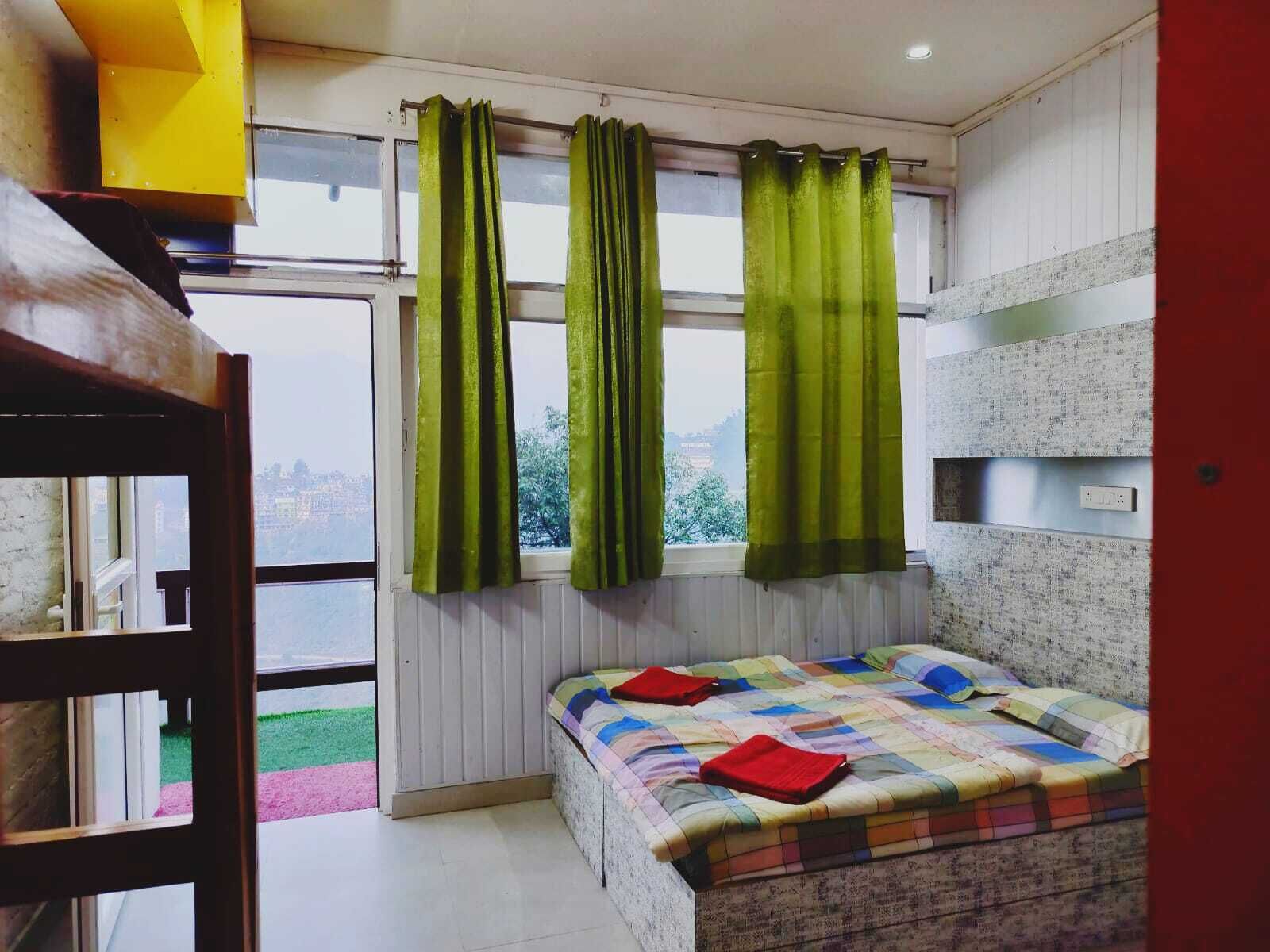 Une chambre à coucher avec un lit, des rideaux verts, une fenêtre et une vue sur le paysage urbain.