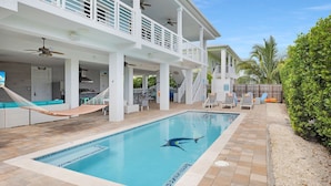 A pool area with a diving board, lounge chairs, and a hammock.