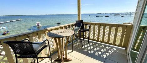 Un balcon avec vue sur l’eau, comprenant une table et deux chaises.