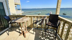 A balcony with a view of the sea, a wooden table, and wicker chairs. - Baywatch E3 (Pensacola Beach)