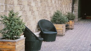 A brick wall with two wicker chairs and potted plants. - Astor (Bishkek)
