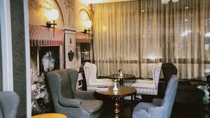 A cozy living room with a fireplace, comfortable seating, and a large window with curtains. - Astor (Bishkek)