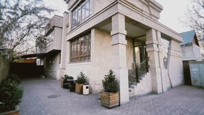 A modern building with a stone facade, large windows, and a staircase leading to the entrance. - Astor (Bishkek)