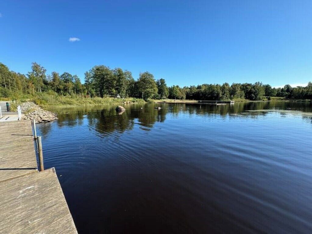 Un lac paisible avec une jetée en bois qui s’avance sur l’eau.