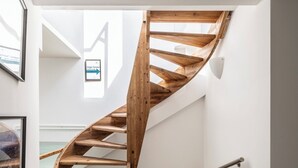 A wooden spiral staircase in a hallway with white walls and a wooden floor. - Suite in Colonne San Lorenzo Milano (Milan)