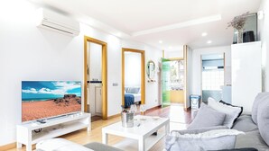 Una sala de estar moderna con televisor, sofá, mesa de centro y vista a la playa.