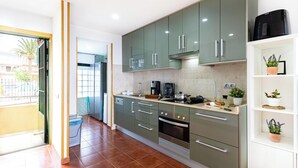 Una cocina moderna con gabinetes verdes, horno empotrado y cafetera.