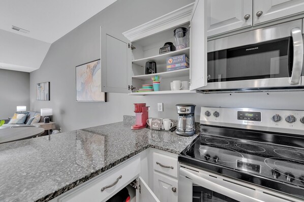 A kitchen with a granite countertop, stainless steel appliances, and a coffee maker.