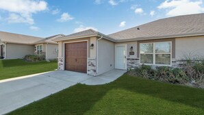 A two-story house with a front garage, a stone accent wall, and a well-maintained lawn.