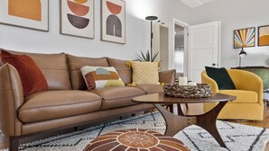 Una sala de estar moderna con un sofá de cuero marrón, un sillón amarillo y una mesa de centro.