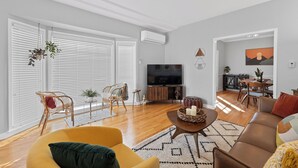 Una sala de estar moderna con un sofá, sillas, un televisor y un comedor.