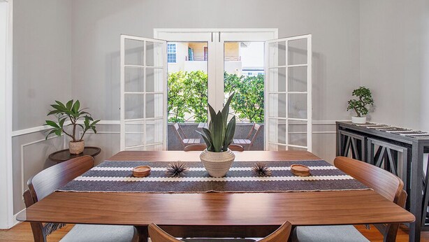 Un comedor con una mesa de madera, sillas y una planta en el centro.