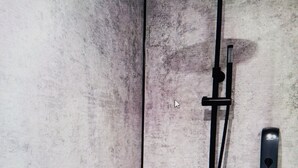 Una ducha moderna con cabezal de mano y panel de control.