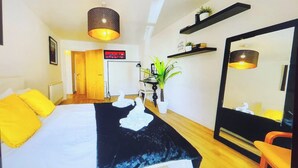 Una habitación de hotel con una cama, un espejo grande, una planta y un estante con adornos.