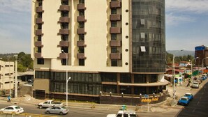 A multi-story hotel with a modern design, featuring balconies and a prominent glass facade. - Holiday Hotel Addis Ababa (Addis Ababa)