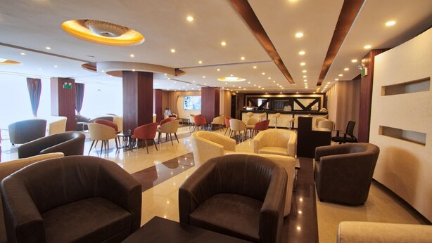 A spacious lobby with leather armchairs, a reception desk, and a piano. - Holiday Hotel Addis Ababa (Addis Ababa)